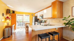 Une cuisine moderne avec des meubles en bois, un grand îlot central doté de tabourets de bar et une vue sur un espace patio.