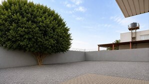 A rooftop terrace with a gravel surface, a paved area, and a large tree. - NOSSO HOTEL (Três Lagoas)