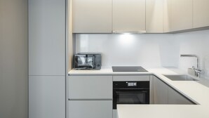 A modern kitchen with white cabinetry, a built-in microwave, a dishwasher, and a sink. - Modern Lisbon W Balcony by Homing (Lisbon)