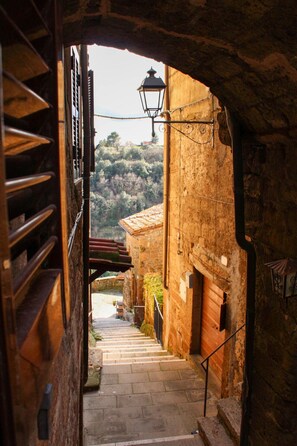 Un escalier étroit en pierre mène à un bâtiment doté d’un toit en tuiles et surmonté d’une lanterne.