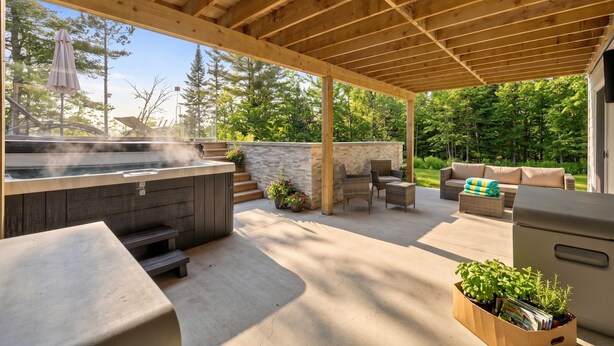 An outdoor patio with a hot tub, seating area, and a grill. - Private Pool, Spa, Pool Table | Chalet Houefifa (Saint-Côme)