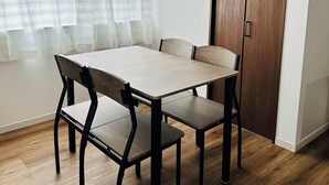 Un comedor con una mesa y sillas, una ventana con cortinas y una puerta de madera.