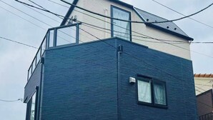 Un edificio de dos pisos con fachada azul oscuro y sección inferior blanca.