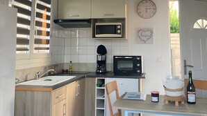 A kitchen with a microwave, coffee maker, and a dining table with chairs.