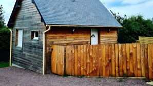 A wooden cabin with a sloped roof, a wooden door, and a fenced area.