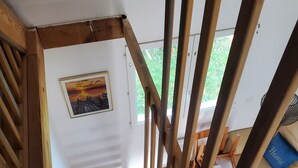 A wooden staircase with a view of a room with a sofa and a painting on the wall.