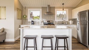 Een moderne keuken met een centraal eiland, roestvrijstalen apparatuur en een hangende lamp.