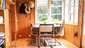 Un intérieur en bois comprenant une table à manger, des chaises et une fenêtre donnant sur un paysage verdoyant.