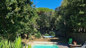 Un jardin avec une piscine, une terrasse en bois et une chaise verte.