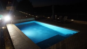 En rektangulär swimmingpool med en kant av kakel, omgiven av en stenbelagd yta.