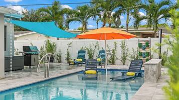 A swimming pool with lounge chairs and a barbecue area.
