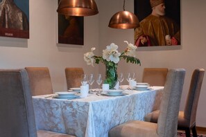 A dining table set for six with a floral centerpiece, surrounded by upholstered chairs. - Ca' Barbarina 1 (Venezia)