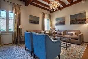 A living room with two sofas, a coffee table, and a chandelier. There are paintings on the walls and a patterned rug on the floor. - Ca' Barbarina 1 (Venezia)