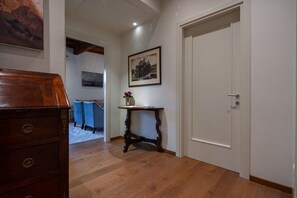 A hallway with a wooden dresser, a table with a vase, and a door. - Ca' Barbarina 1 (Venezia)