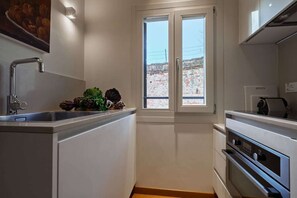 A compact kitchen with a window, a sink, and a built-in oven. - Ca' Barbarina 1 (Venezia)