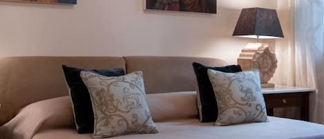 Ein Hotelzimmer mit einem Bett, zwei Zierkissen, einem Nachttisch mit Lampe und Wandbildern.