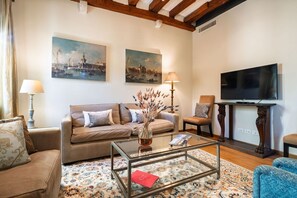 A living room with a sofa, armchairs, a coffee table, a TV, and artwork on the walls. - Two bedrooms apartment with Terrace in Castello (Venezia)