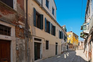 A narrow street with buildings featuring traditional architecture, including shuttered windows and a mix of brick and plaster facades. - Ca' Barbarina 1 (Venezia)