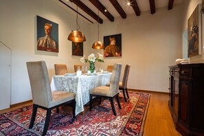 A dining area with a table set for four, surrounded by chairs, a patterned rug, and artwork on the walls. - Ca' Barbarina 1 (Venezia)