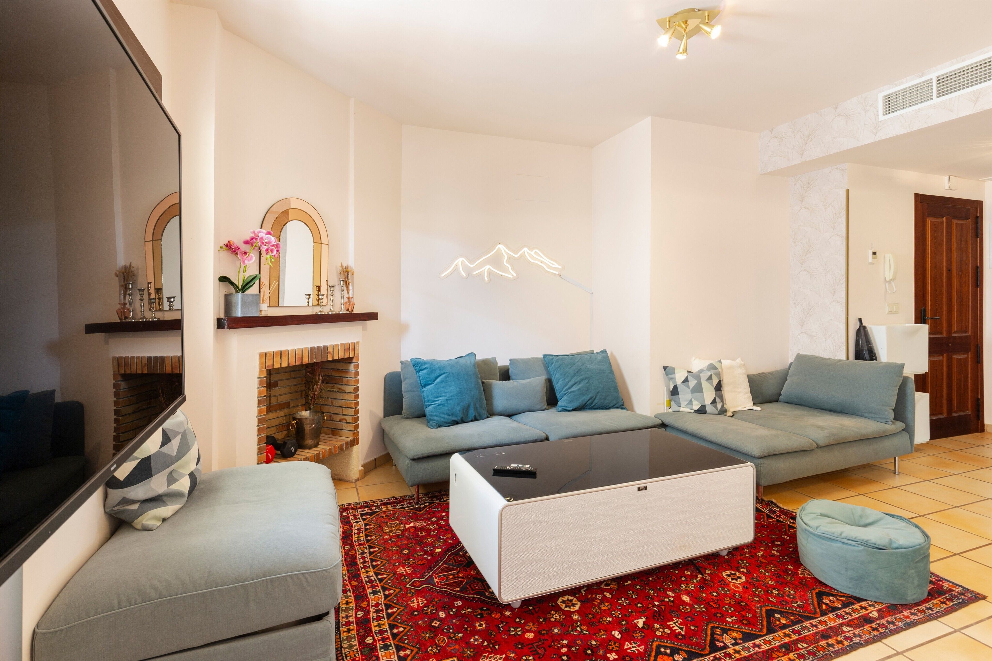 Una sala de estar moderna con un sofá, una mesa de centro, un televisor y una chimenea.