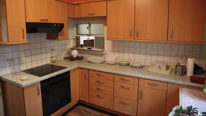 Eine Küche mit Holzschränken, einem Geschirrspüler, einer Mikrowelle und einer gefliesten Spritzschutzwand.