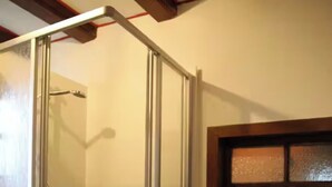 Ein Badezimmer mit einer Duschkabine, einem Waschbecken und einem Fenster über dem Spiegel.
