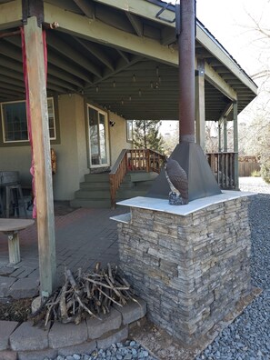A covered outdoor area with a stone fireplace, wooden steps, and a railing. - 3BR Entire Home-Dog Friendly- Near DIA & Golf Course - Hot Tub (Denver)