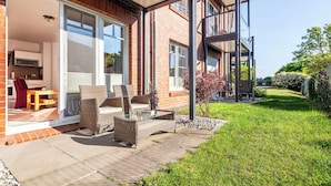 Ett modernt hus med en uteplats som har möbler av rotting och ett bord i glas.