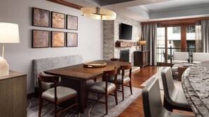 A modern living room with a dining area, a fireplace, and a TV mounted on a brick wall. - Spacious 3-bedroom, 3.5 Bath Exclusive Ritz-Carlton Resort in gorgeous Vail (Vail)
