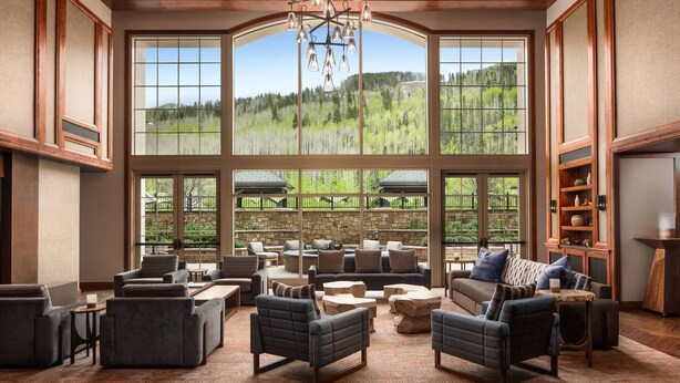 A spacious living area with large windows, comfortable seating, and a view of a forested landscape. - Spacious 3-bedroom, 3.5 Bath Exclusive Ritz-Carlton Resort in gorgeous Vail (Vail)