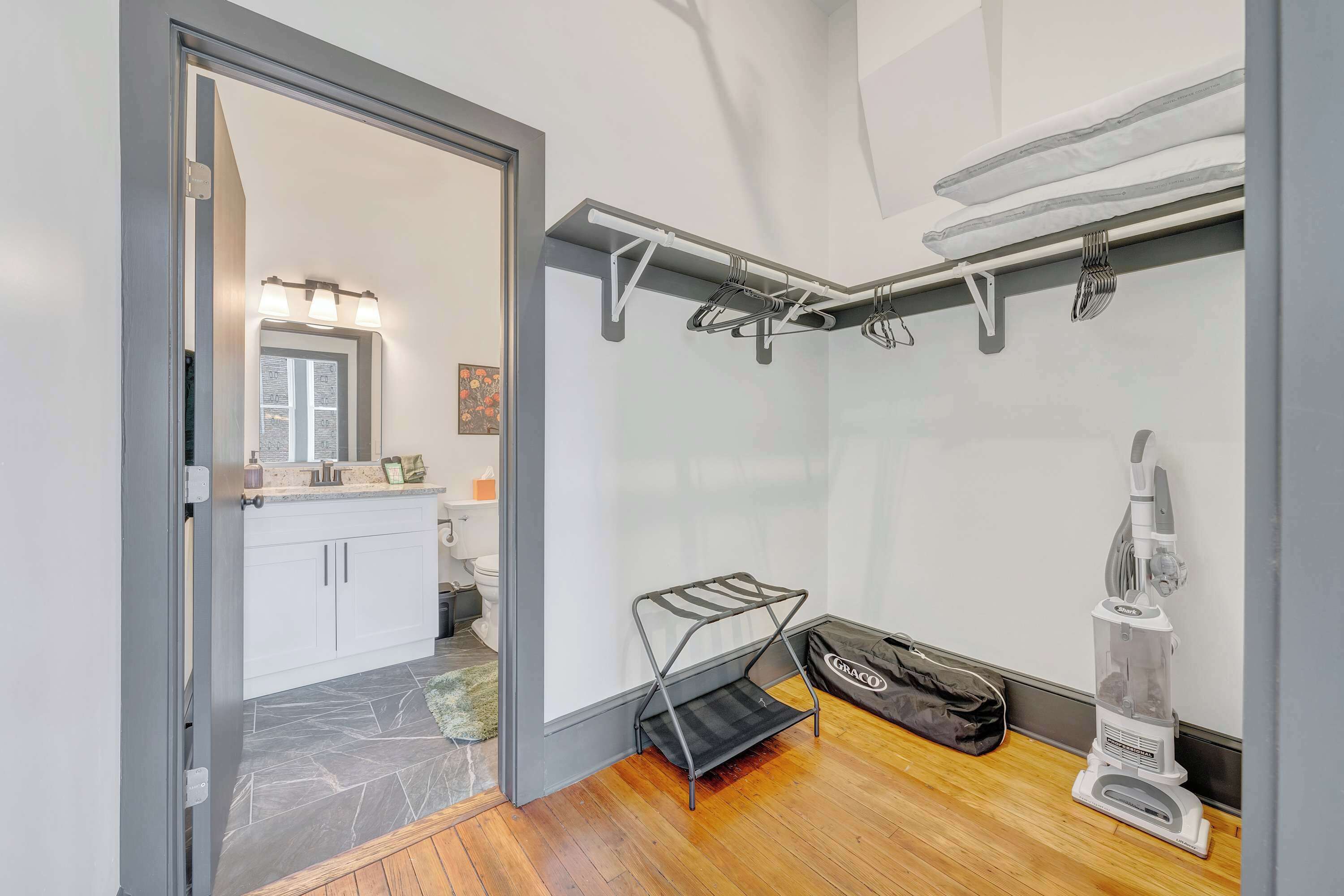 A modern bathroom with a shower, a toilet, and a sink. There is a vacuum cleaner and a bag on the floor.
