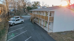A two-story building with a wooden deck and a covered parking area. - Stay Roanoke | Charming 1BR Near Hospital & City (Roanoke)