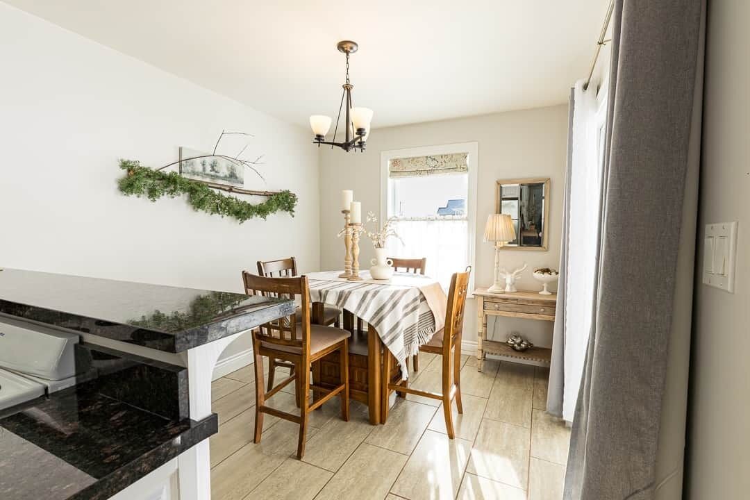 Une cuisine dotée d’un plan de travail en marbre, de chaises en bois, d’une table à manger et d’un lustre.