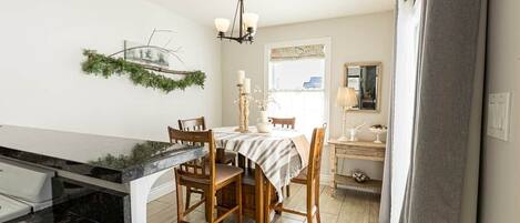 Une cuisine dotée d’un plan de travail en marbre, de chaises en bois, d’une table à manger et d’un lustre.