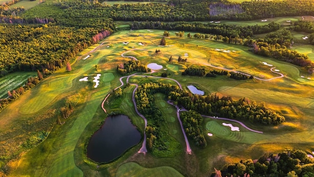 An aerial view of a golf course with multiple bunkers, water hazards, and winding fairways.