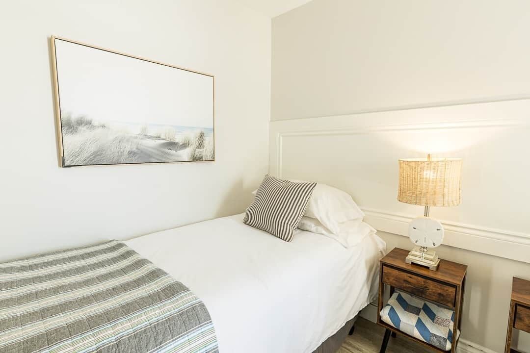 Une chambre à coucher avec un lit, une table de chevet avec une lampe, un oreiller et une couverture.