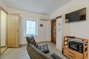 A living room with a sofa, a TV mounted on the wall, a wooden door, and a window. - GuestHost - A cozy 40 sq m apartment that comfortably accommodates two people, located on the third floor of a period building with an elevator. The apartment is centrally located in the Quadrilatero neighborhood, just steps from Piazza della Consolata a (Turin)