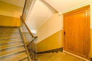 A staircase with a wooden handrail and metal balusters, leading to a wooden door. - GuestHost - A cozy 40 sq m apartment that comfortably accommodates two people, located on the third floor of a period building with an elevator. The apartment is centrally located in the Quadrilatero neighborhood, just steps from Piazza della Consolata a (Turin)