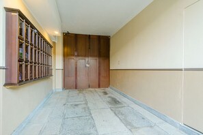 Ein Flur mit Holztür, Metallgeländer und Fliesenboden.