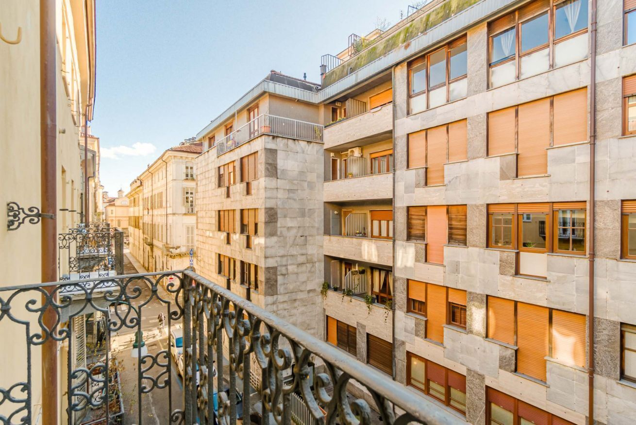 A multi-story building with balconies, a narrow street, and a wrought iron railing.
