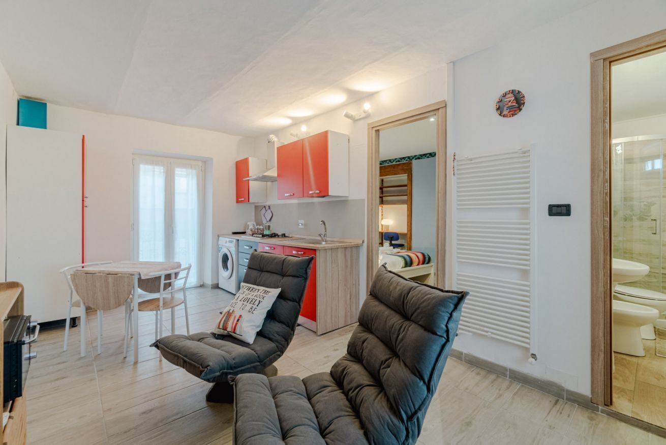 Een kleine leefruimte met een kitchenette, een eethoek en een badkamer.