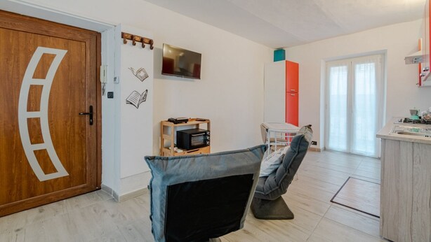 A room with a wooden door, a television, a small kitchenette, and a window. - GuestHost - A cozy 40 sq m apartment that comfortably accommodates two people, located on the third floor of a period building with an elevator. The apartment is centrally located in the Quadrilatero neighborhood, just steps from Piazza della Consolata a (Turin)