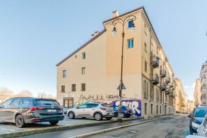 Eine Straße mit parkenden Autos, einem Gebäude mit Graffiti und einer Straßenlaterne.