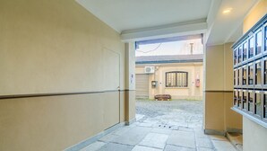 A corridor with stone flooring, beige walls, and a view of a building with a window and a door. - GuestHost - A cozy 40 sq m apartment that comfortably accommodates two people, located on the third floor of a period building with an elevator. The apartment is centrally located in the Quadrilatero neighborhood, just steps from Piazza della Consolata a (Turin)