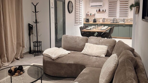 A modern living room with a sectional sofa, a glass coffee table, and a dining area in the background. - Spacious house near the lake - 6 people (Saint-Épain)