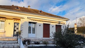 A two-story house with a tiled roof, a front entrance with steps, and a small garden area. - Spacious house near the lake - 6 people (Saint-Épain)