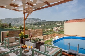 Eine Dachterrasse mit Swimmingpool, Gartenmöbeln und Blick auf die umliegende Landschaft.