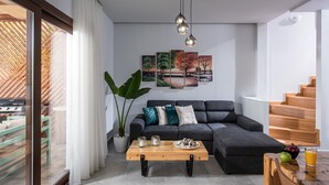 A modern living room with a dark grey sofa, a wooden coffee table, and a staircase. - Iris Villa 3 (Archanes-Asterousia)