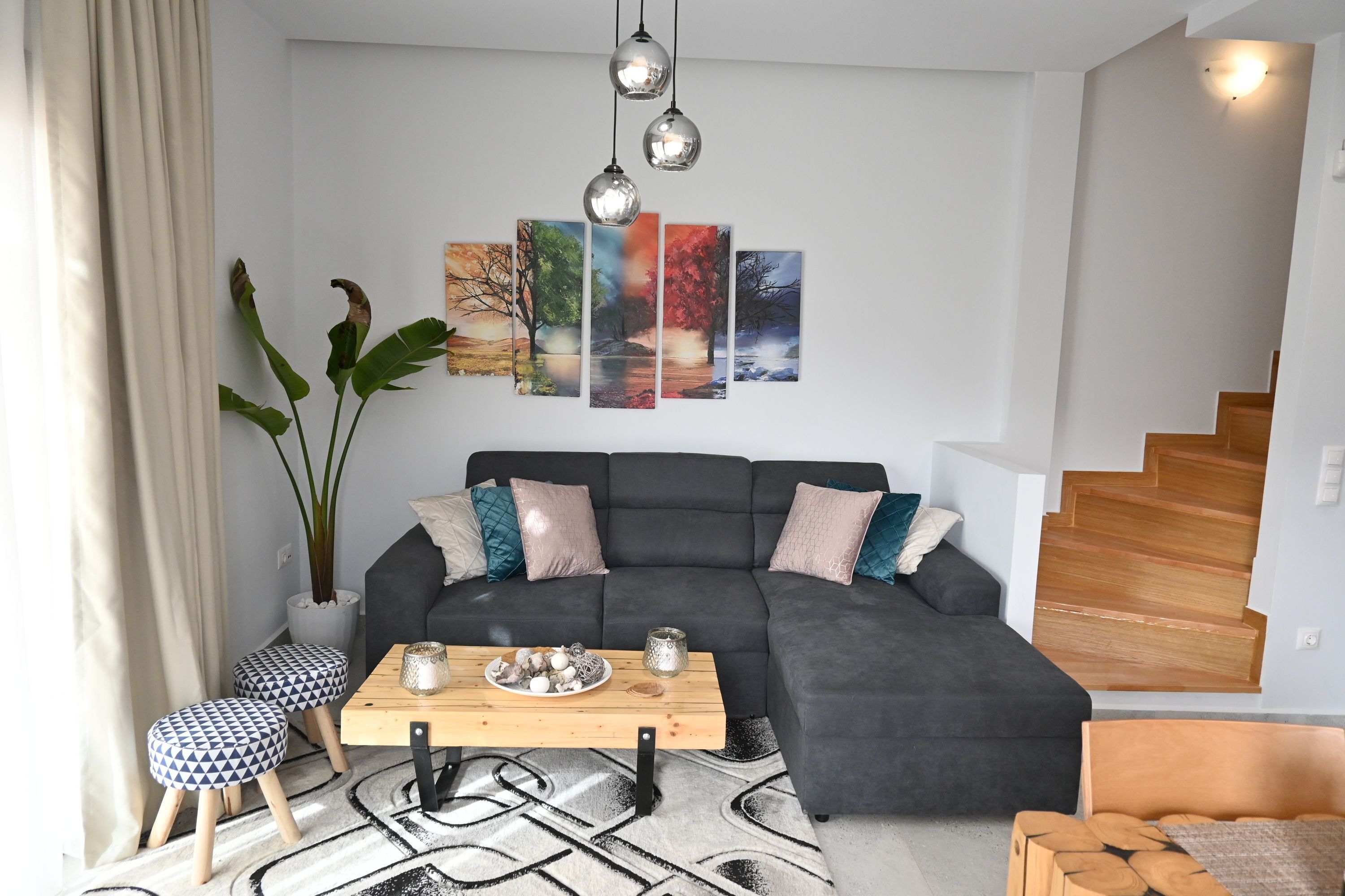 A modern living room with a grey sectional sofa, a wooden coffee table, and a large abstract painting on the wall.