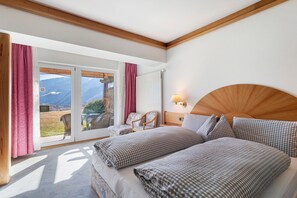 Une chambre à coucher avec un lit, une chaise, une lampe et une vue sur l’extérieur.